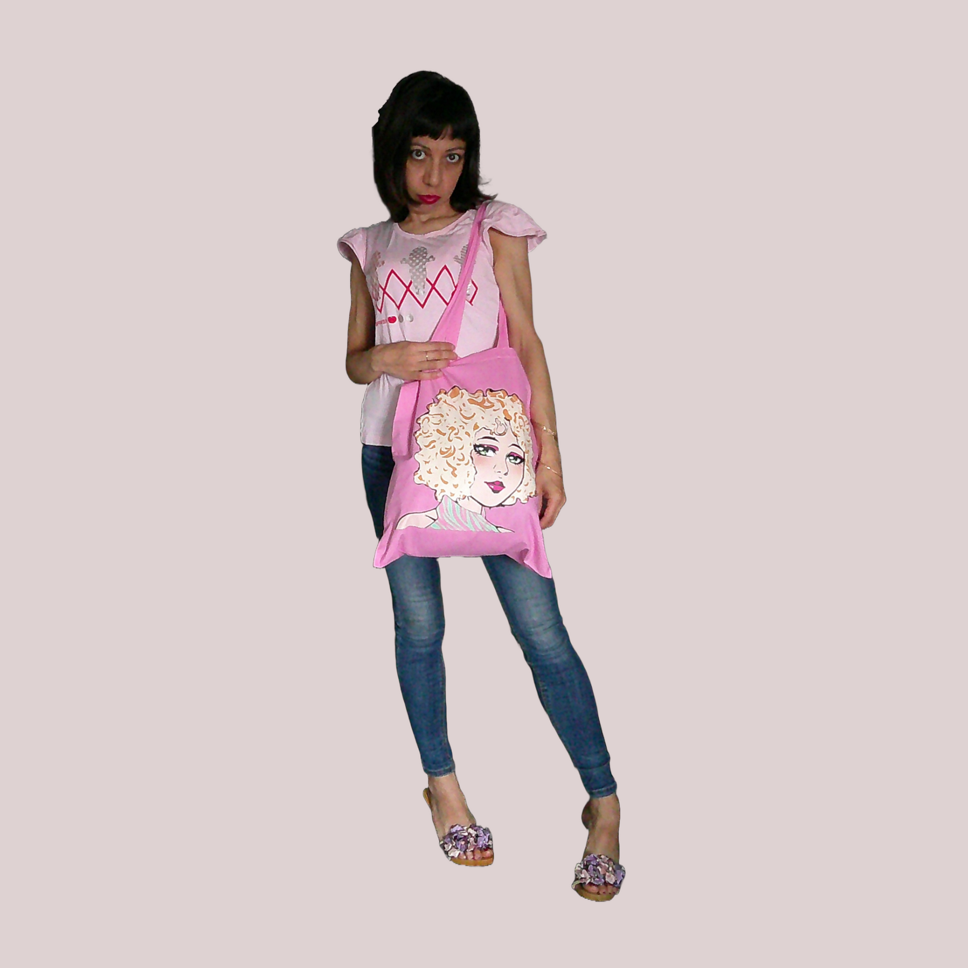 Woman holding a pink tote bag with a graphic design on a plain background