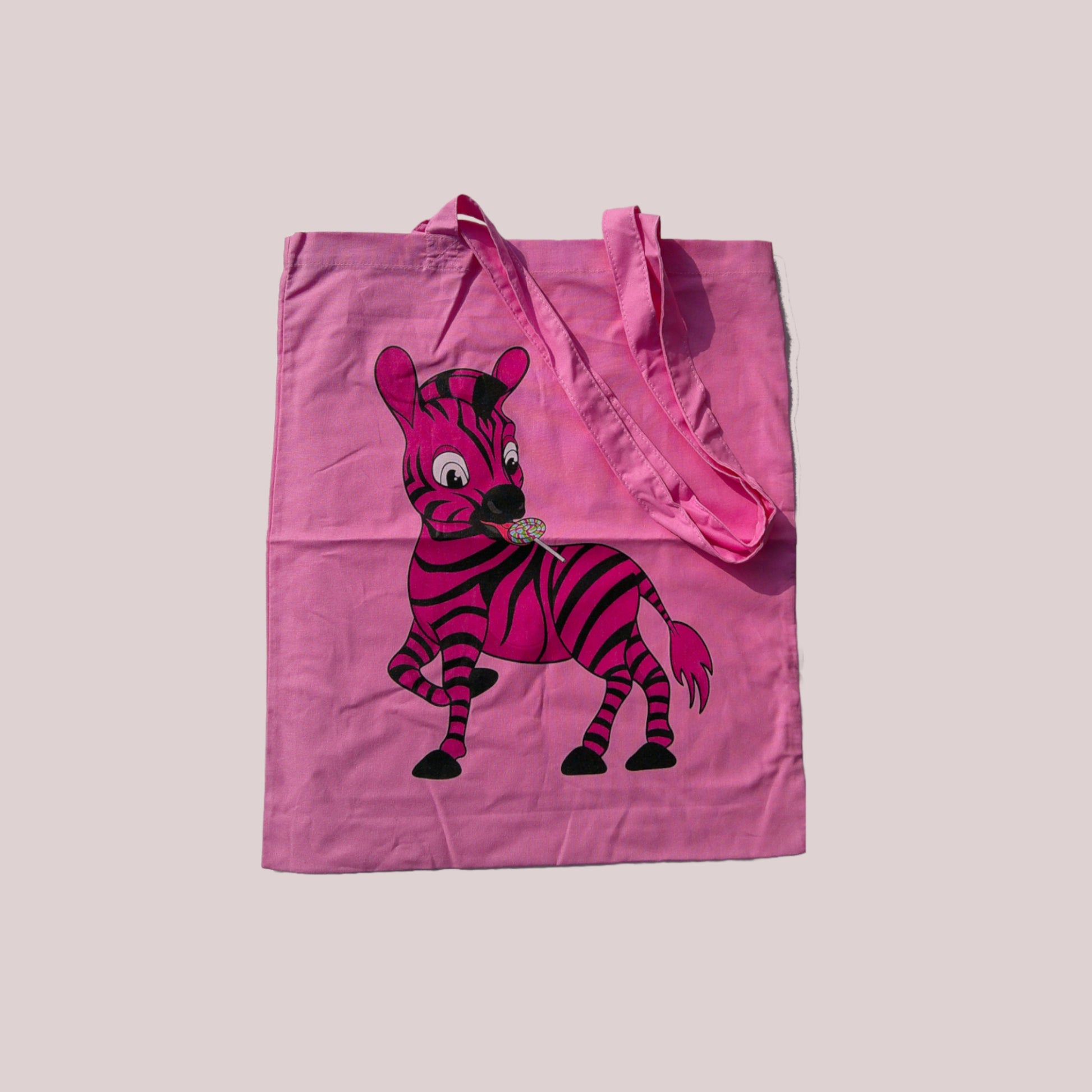 Pink tote bag with a cartoon zebra design on a light grey background