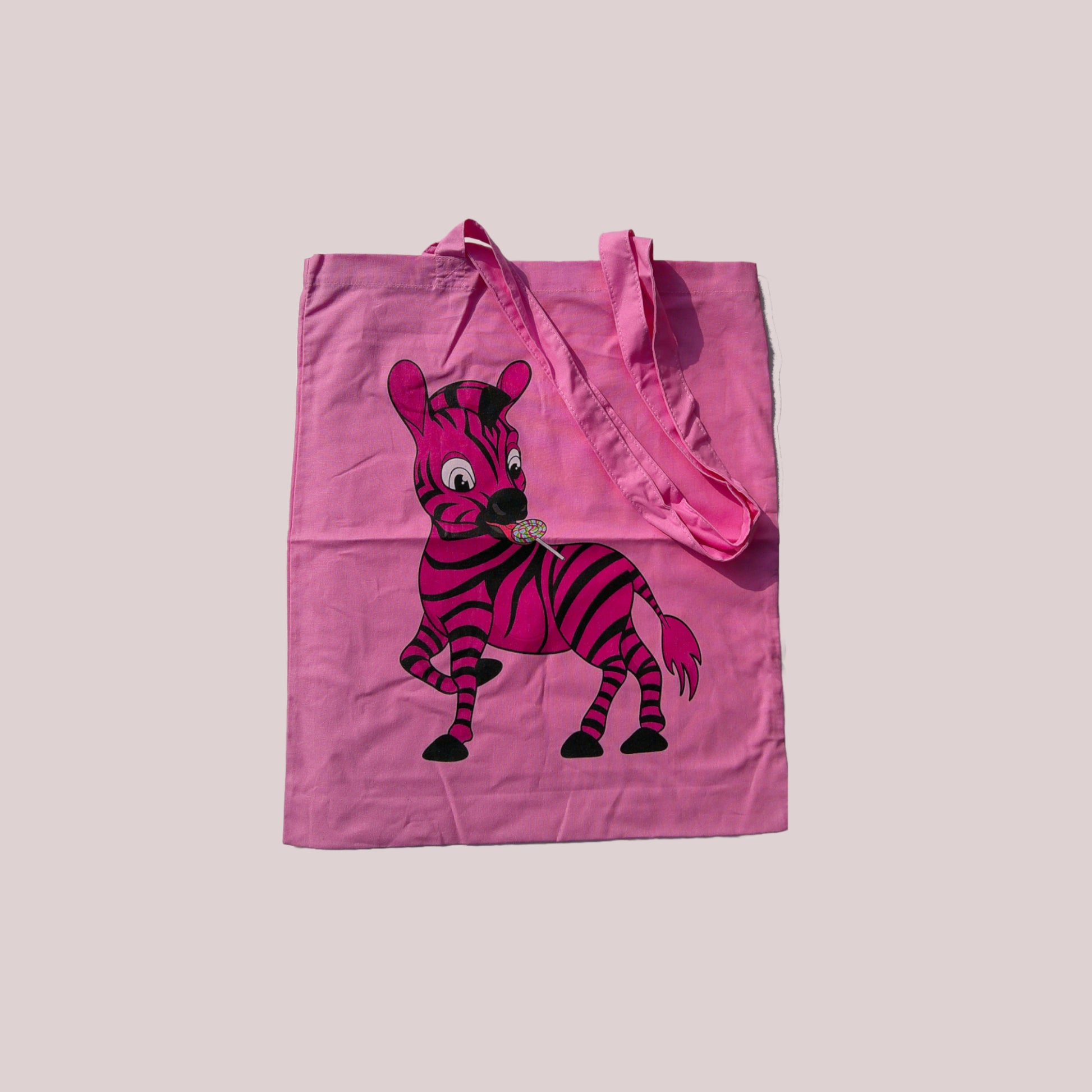 Pink tote bag with a cartoon zebra design on a light grey background